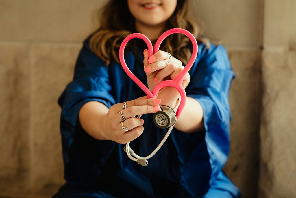A nurse holding a red stethoscope, shaped in a love shape.