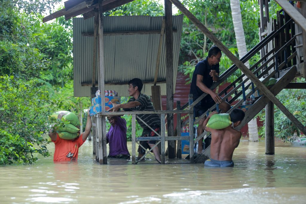 A flooding disaster and people bringing food and relief materials